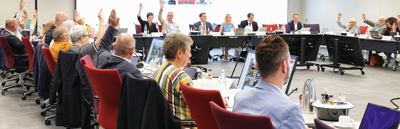 Sitzung des Verwaltungsrates, viele Personen sitzen u-förmig in einem Konferenzraum