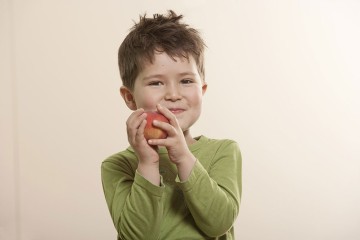 Das Bild zeigt einen kleinen Jungen mit einem Apfel.
