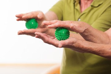 Zwei Handpaare machen Übungen mit jeweils einem Igelball.