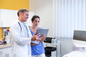 Ein Arzt und eine Krankenschwester schauen zusammen auf ein Tablet