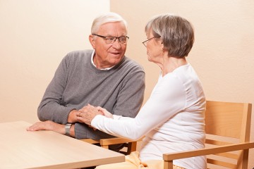 Zwei Pflegebedürftige sitzen am Tisch und unterhalten sich.