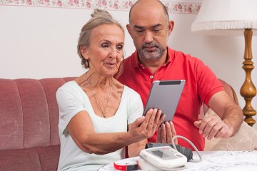 Ein Pfleger erklärt einer Pflegebedürftigen die Nutzung eines Tablets.