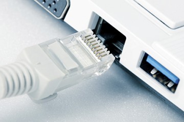 ein LAN-Kabel vor einen LAN-Anschluss an einem Computer